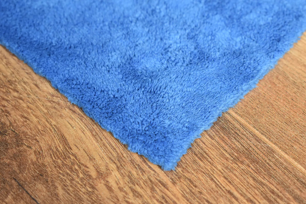 Plush coral fleece microfiber towel close-up showing brushed plush fiber surface and edgeless edge - color blue